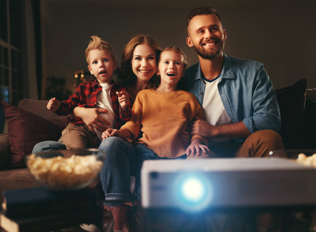 family mother father and children watching projector, TV, movies with popcorn in   evening   at home